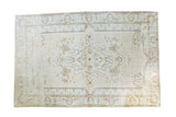 Distressed Oushak rug with ornate central medallion and lotus flower border, near-white field.