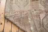 Distressed Oushak rug pile revealing textured wool, soft earth tones, and subtle rosy hues at the fold.