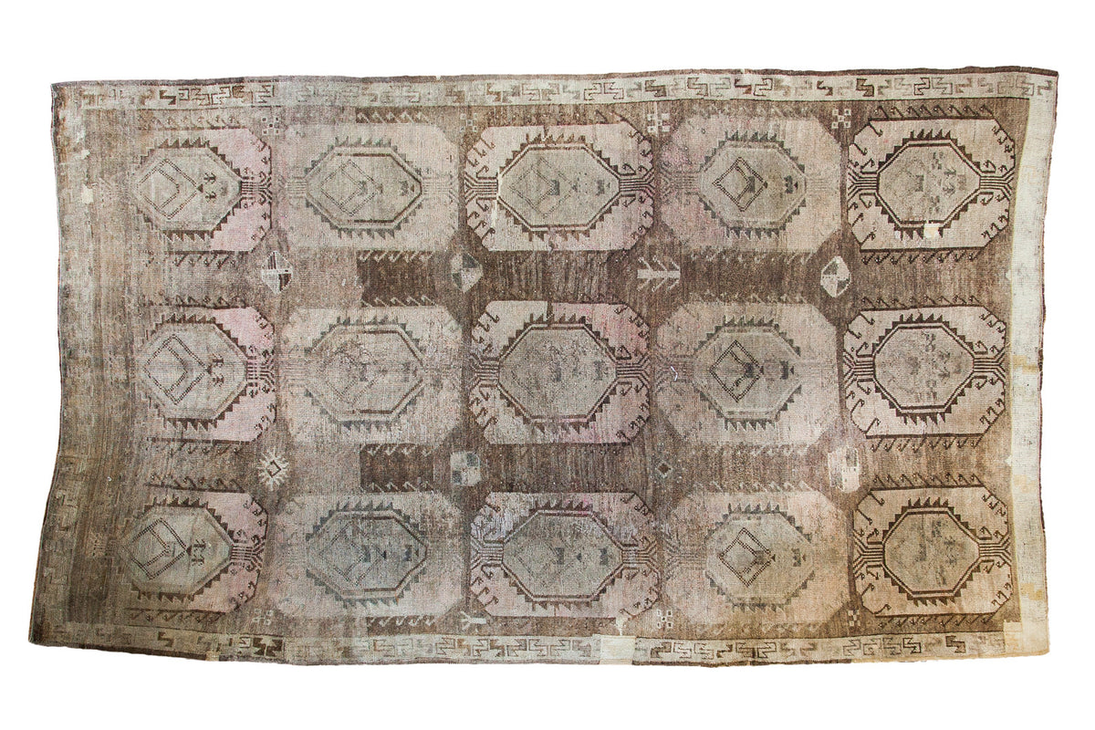 Distressed vintage Oushak rug, large geometric medallions, muted earth tones, faded mauve and beige.