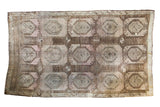 Distressed vintage Oushak rug, large geometric medallions, muted earth tones, faded mauve and beige.