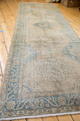 Corner of the distressed Oushak runner, showing teal scrolling palmette border and softened medallion.