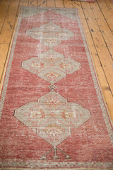 Slate grey oversize medallion with geometric design on the distressed cinnabar red Oushak runner.