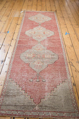 Distressed Oushak runner's cinnabar red field, geometric mehrab, and slate grey border.