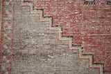 Textural stepped geometric border of distressed Oushak rug with cinnabar red and slate grey.