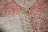 Distressed Oushak runner folded, showing hand-knotted back and cinnabar pile with grey motif.