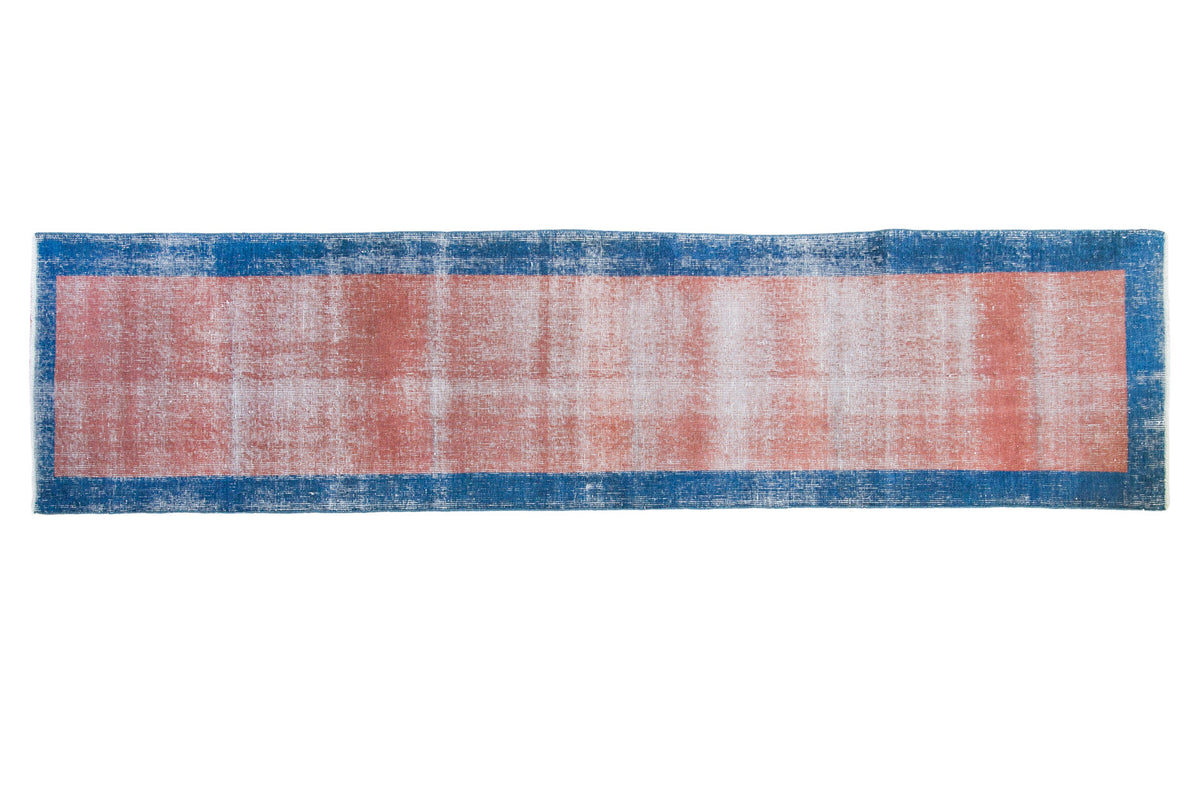Distressed hand-knotted Oushak runner with a faded pink field and blue border, 2'3" x 9'1".