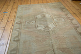 Distressed vintage Oushak runner featuring large geometric medallion and soft earth tone palette.