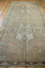 Distressed Oushak runner section with muted geometric patterns in soft beige and smokey rose.