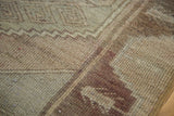 Distressed Oushak runner with soft earth tone geometric patterns and textured pile.