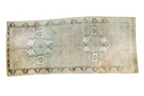 Distressed vintage Oushak runner with geometric medallions in smokey rose and silver-grey earth tones.
