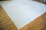 Bleached ivory dhurrie flatweave carpet with subtle beige stripes, showcasing longitudinal seams.
