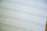 Finely woven dhurrie flatweave texture in bleached ivory with platinum stripes.