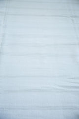 Fine dhurrie flatweave texture of a bleached ivory rug with subtle light beige and silver stripes.