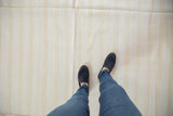 Bleached ivory dhurrie flatweave rug with fine beige stripes and visible seam detail.