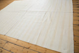 Cotton dhurrie flatweave texture, bleached ivory with subtle beige stripes and professional seam.