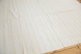 Vintage flatwoven carpet with visible seam, displaying bleached ivory and beige striped dhurrie weave.