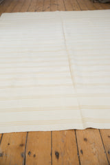 Finely woven dhurrie texture with subtle beige stripes on a vintage ivory flatweave.