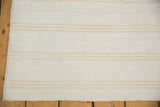 Close-up of fine dhurrie weave showing bleached ivory and beige stripes.
