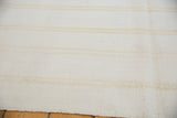 Handwoven dhurrie texture of bleached ivory and subtle beige striped vintage carpet.