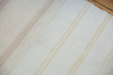 Finely woven cotton dhurrie texture in pure ivory with subtle beige stripes.
