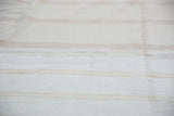 Vintage handwoven cotton dhurrie, bleached ivory with subtle beige stripes, showing seams.