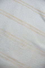 Finely woven dhurrie texture, bleached ivory and pale gold stripe detail.