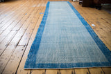 Textured light blue field and narrow deep blue border of the distressed Oushak runner.