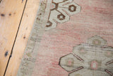 Blanched pale rose and bronze curvilinear motif texture on a vintage Oushak rug.