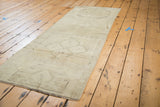 Creamy beige vintage Oushak runner, diagonally presented, with faint medallion pattern.