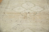 Faint medallion patterns on the creamy beige hand-knotted pile of a vintage Oushak rug.