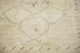 Creamy beige hand-knotted pile texture with subtle curvilinear medallion motif.