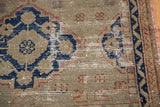 Worn navy motifs and terra cotta accents on the distressed pile of a vintage Oushak runner.
