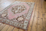Distressed Oushak rug showcasing faded rose, charcoal bronze tones, and textured pile.