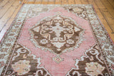 Distressed deep rose Oushak rug border, with faded tangerine and charcoal bronze patterns.