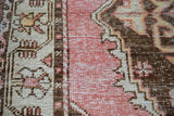 Distressed vintage Oushak rug pile, showing faded rose, charcoal, ivory, and soft tangerine patterns.