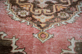 Distressed Oushak rug texture detail with faded rose, bronze, and tangerine patterns.