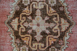 Distressed Oushak rug with intricate bronze, ivory, and faded tangerine motifs on rose.