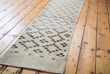 Distressed texture and geometric pattern of ivory, silver, charcoal Oushak runner.