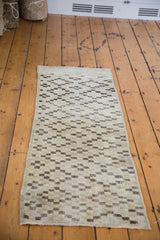 Distressed aesthetic of the vintage Oushak runner's geometric pattern in ivory, beige, and charcoal.