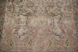 Close-up of distressed low pile with etched red and sage floral motifs.