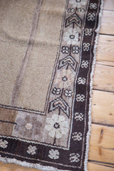 Distressed Oushak border, natural wool tones, geometric motifs, and abrash field.