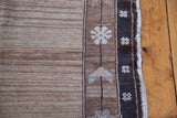 Distressed Oushak border showing natural brown wool, abrash, and delicate floral motifs.