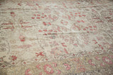 Distressed vintage Oushak carpet with rosey cinnabar floral vines on an ivory field.