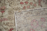 Vintage Oushak rug showing detailed hand-knotted weave, distressed pile, rosy floral motifs.