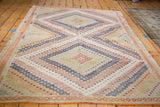 Repeating geometric diamond and zig-zag patterns in pastel orange, blue, and cream Jajim rug.