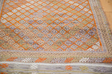 Distressed Jijim rug with geometric orange diamonds, textured pile, and multi-toned woven border.