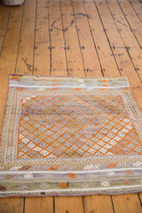 Tangerine orange diamond patterns with muted striped borders on this distressed Jijim rug.