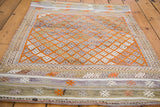 Distressed hand woven Jijim rug with tangerine orange geometric diamond lattice, silver, and earthy tones.
