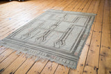Distressed silvery sea foam green Jijim rug, angled view revealing linear geometric patterns and fringe.