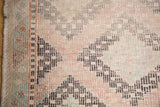 Corner detail of hand-woven vintage Jijim geometric pattern in seafoam, grapefruit, aubergine.